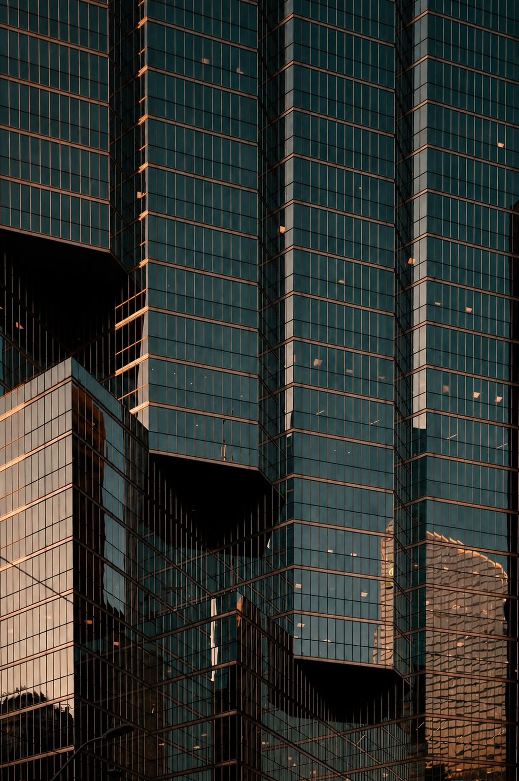Arquitetura corporativa em vidro, com linhas verticais e reflexos dourados.